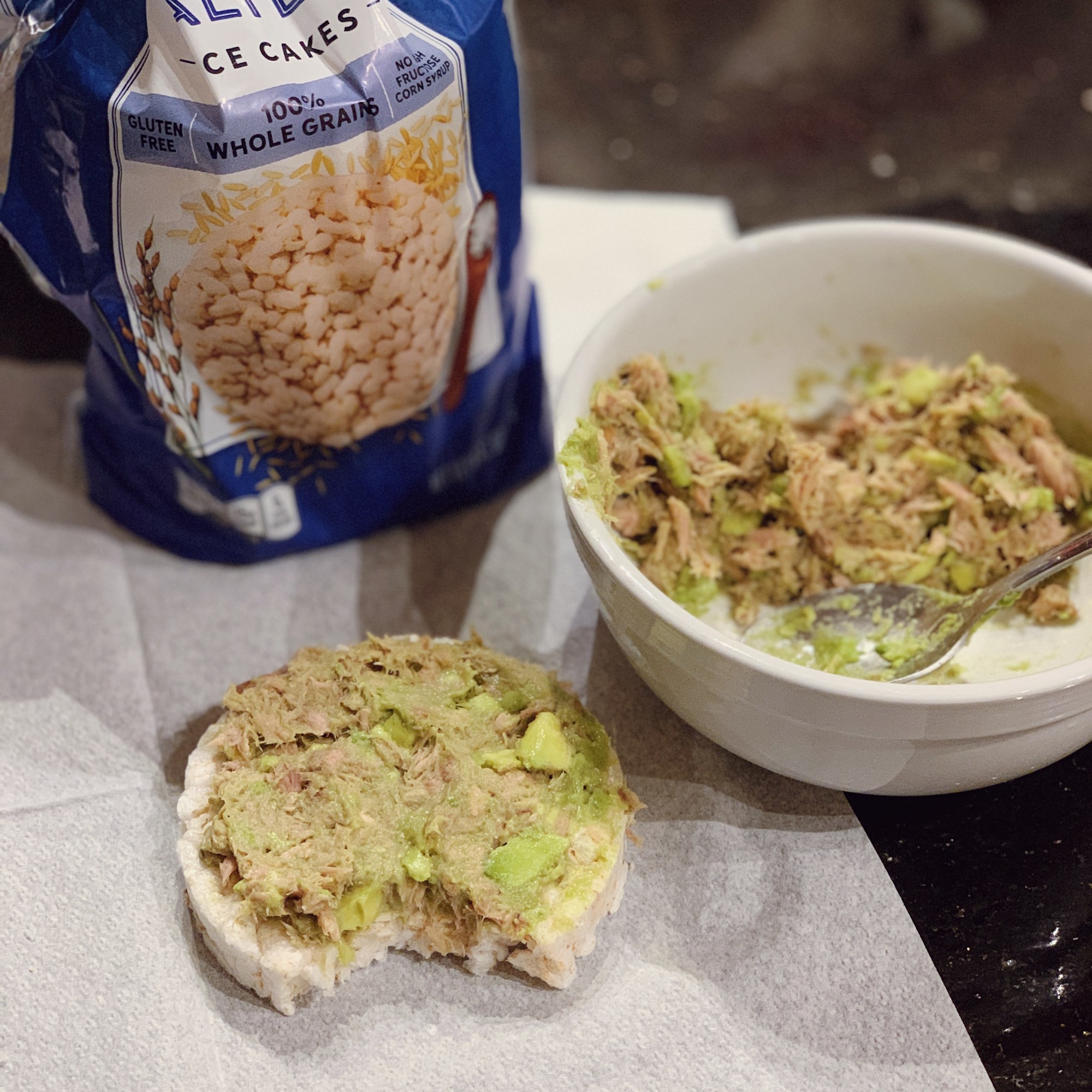 a photo of a whole grain cake with mixed canned tuna and fresh avocado