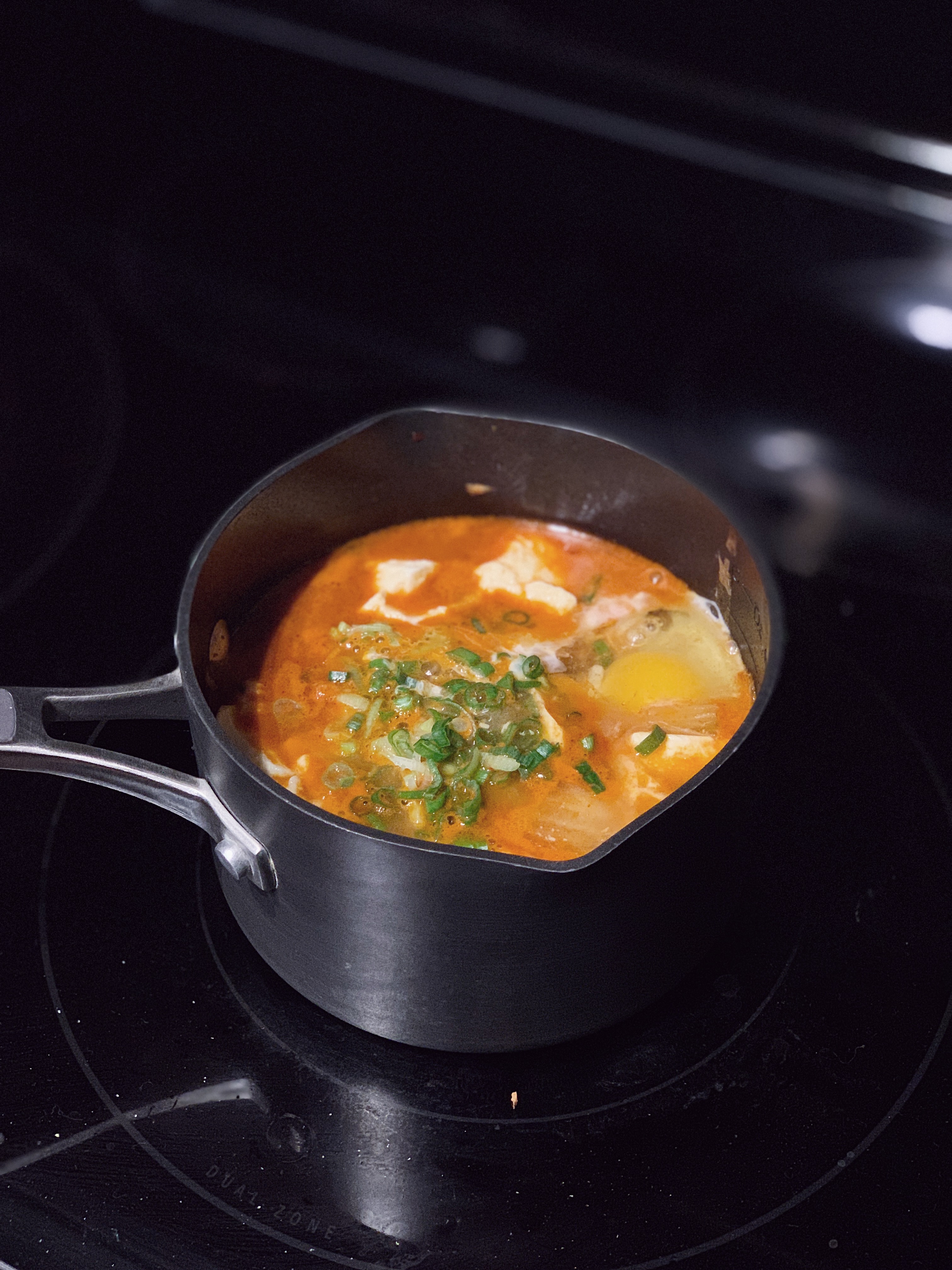 a small pot of kimchi soondubu jigae on a stovetop