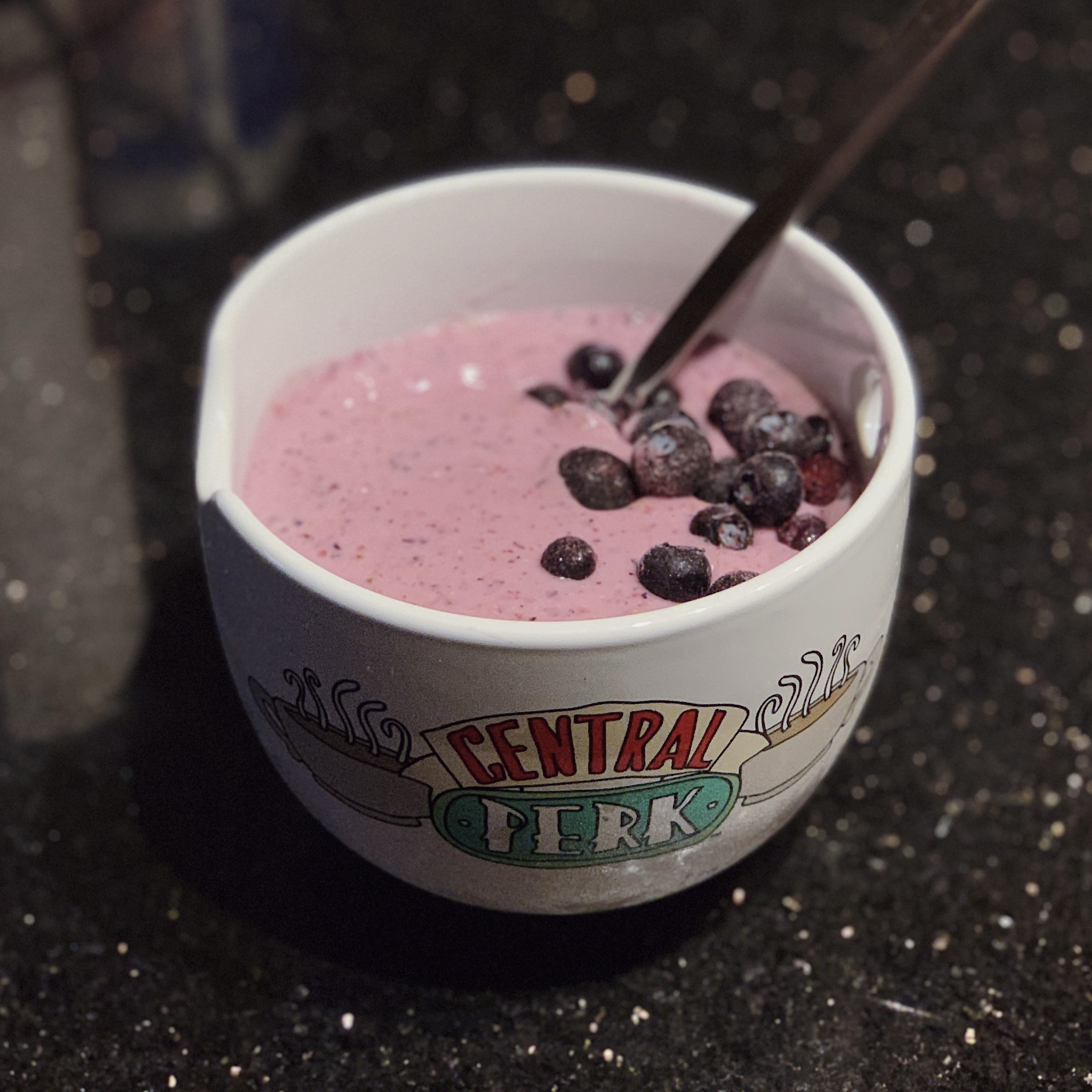 a photo of a Central Perk-themed ramen bowl filled with a Coconut Berry Smoothie with blueberries on top