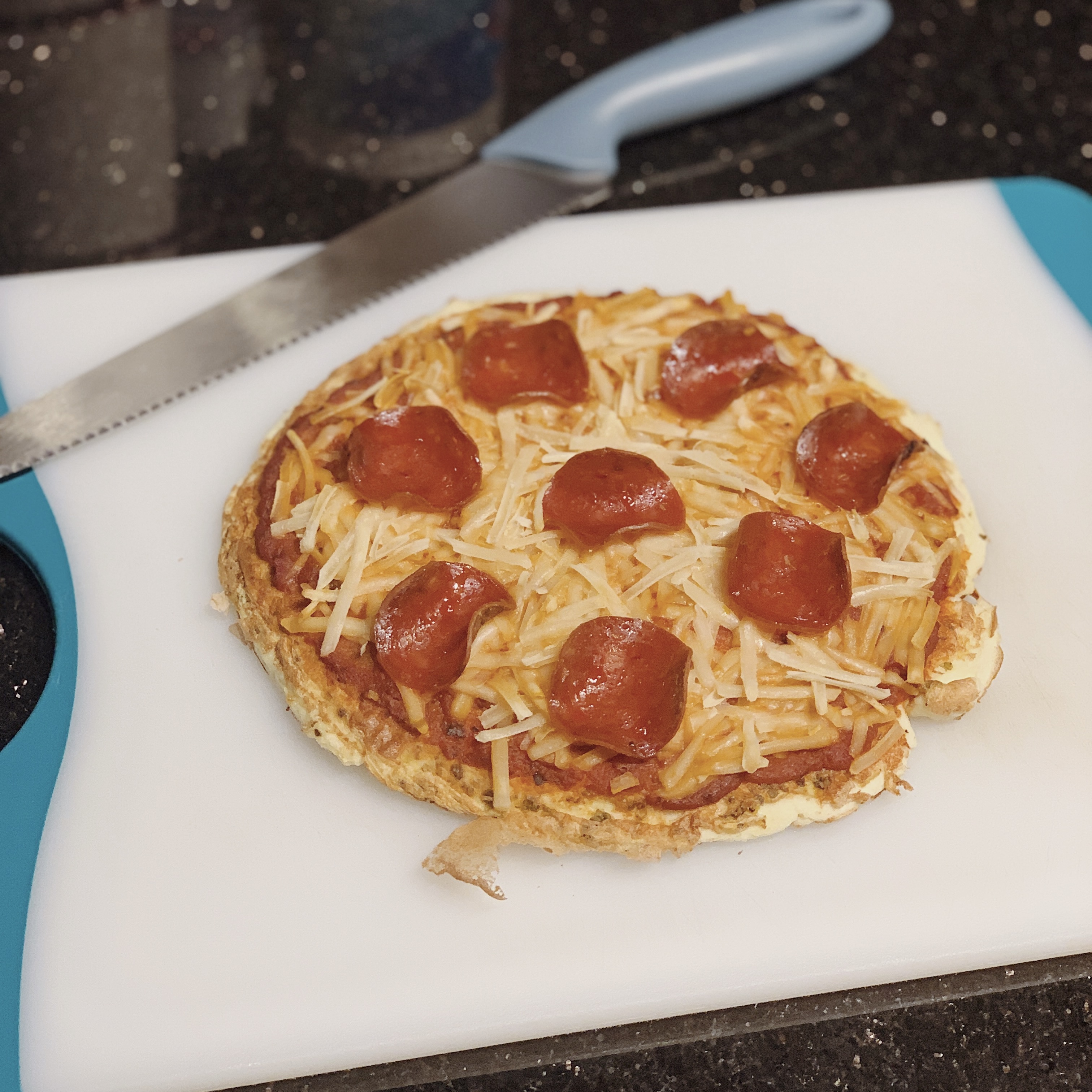 an 8-gram carb pizza sitting on a cutting board with plant-based cheese, turkey pepperoni and organic sauce