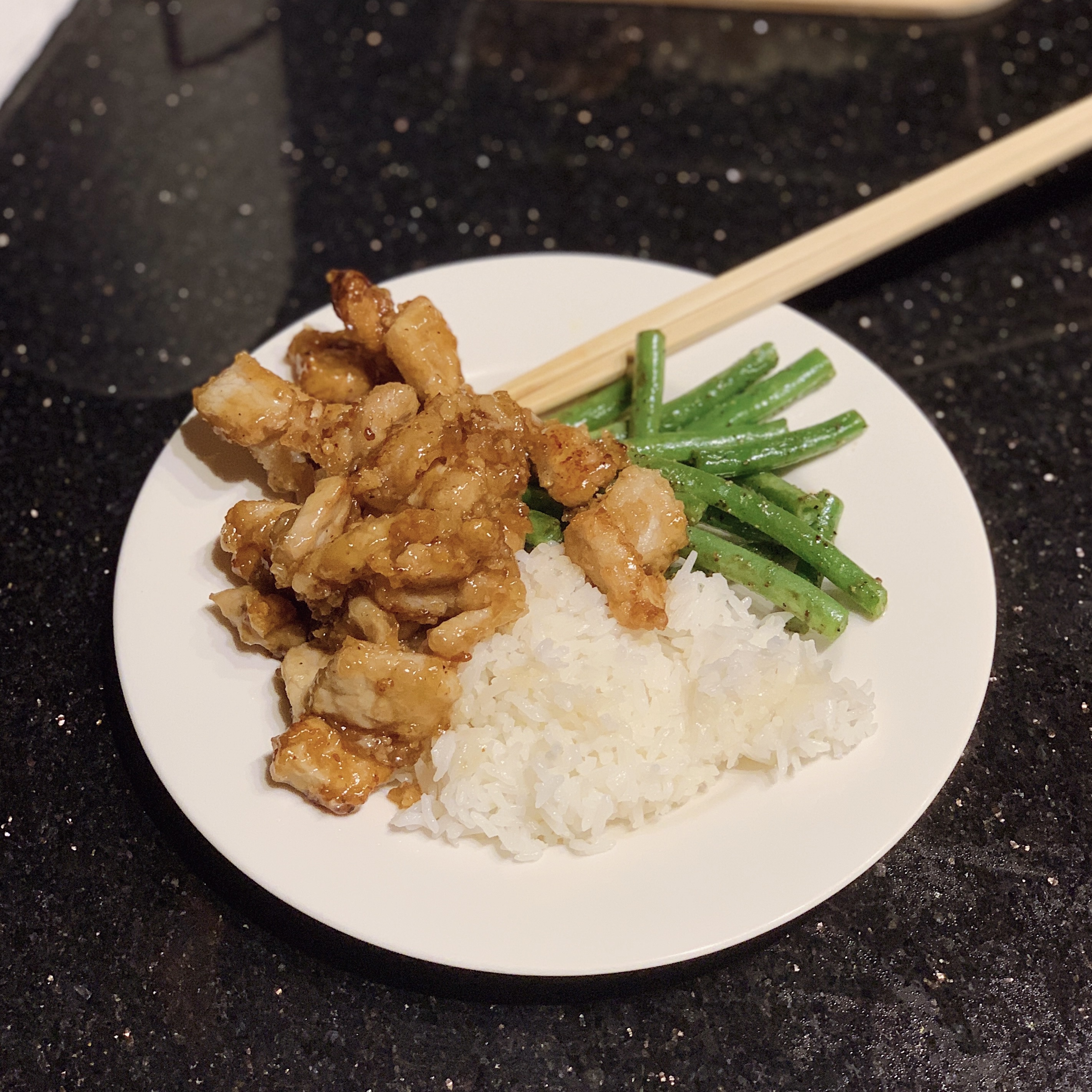 A bowl of Honey Garlic Pork with white jasmine rice and roasted green beans.