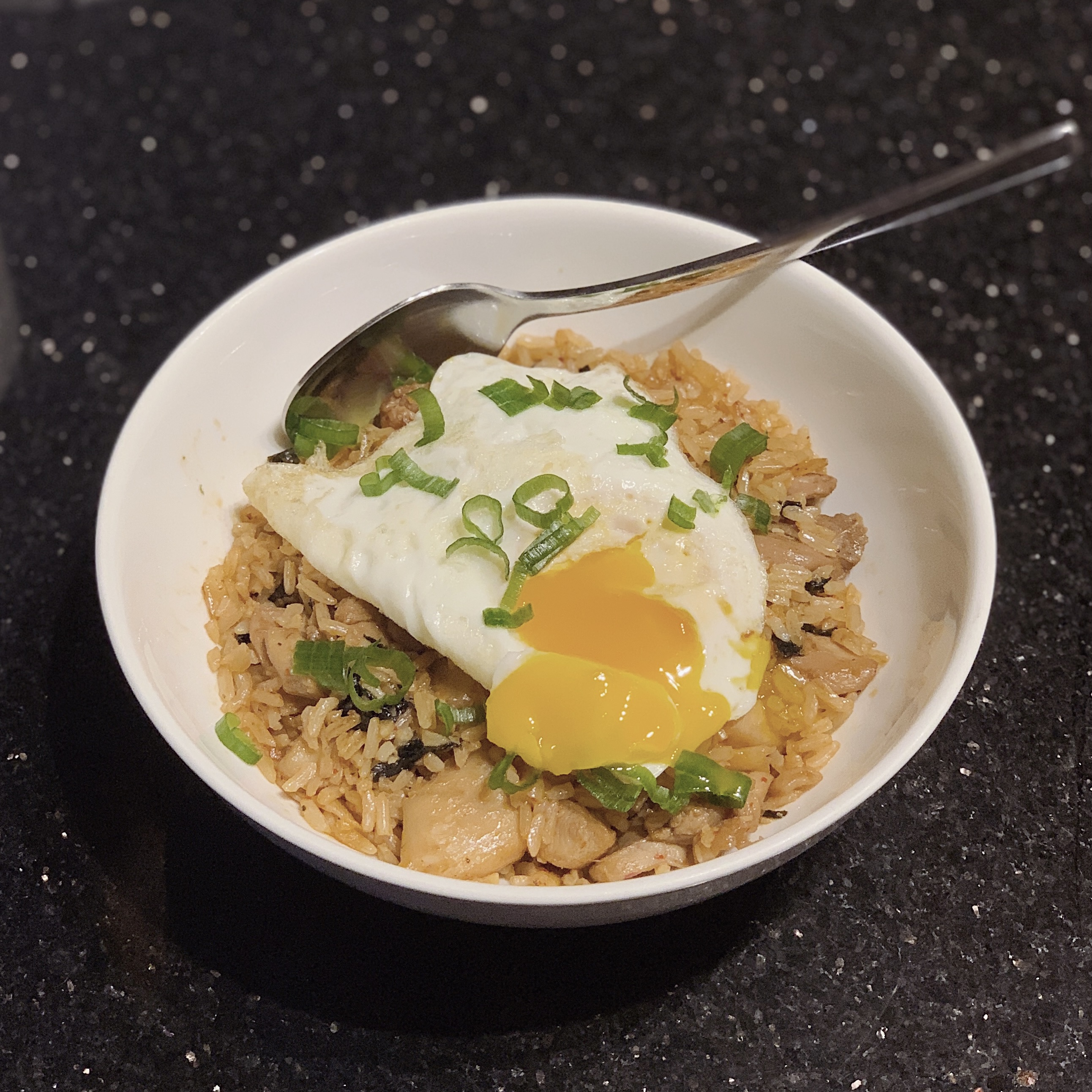 A bowl of fried rice with kimchi, chicken and over-easy egg.