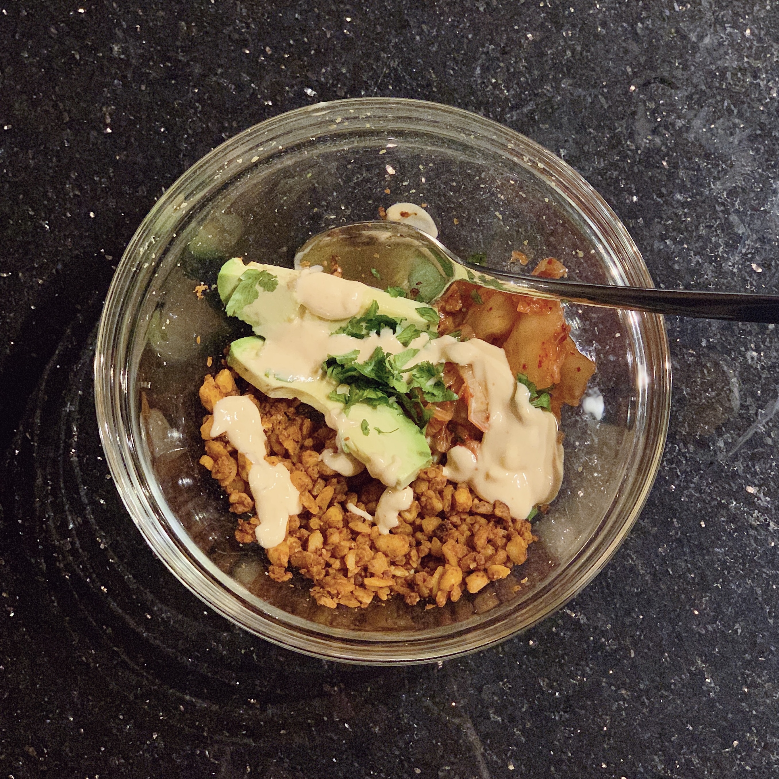 Kimchi tempeh taco bowl with kimchi, tempeh, avocado, sauce and cilantro
