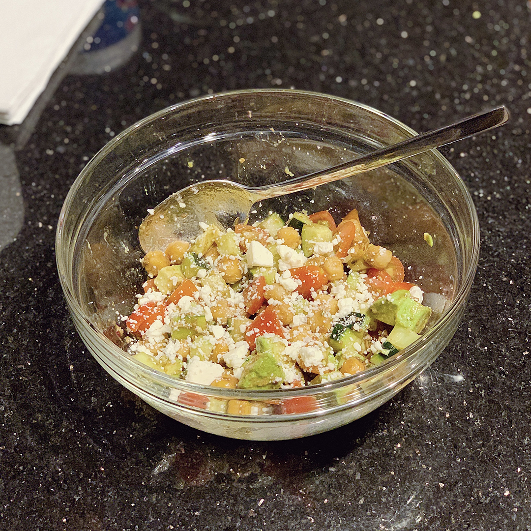 A glass bowl with a spoon and Balsamic Salad.