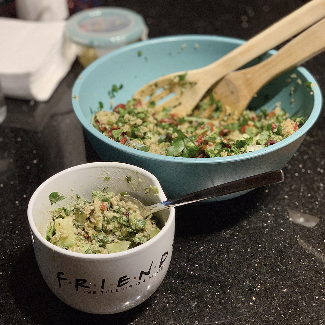 A countertop with a large salad mixing bowl and a "Friends" serving bowl with Tabbouleh Jen Aniston Salad.