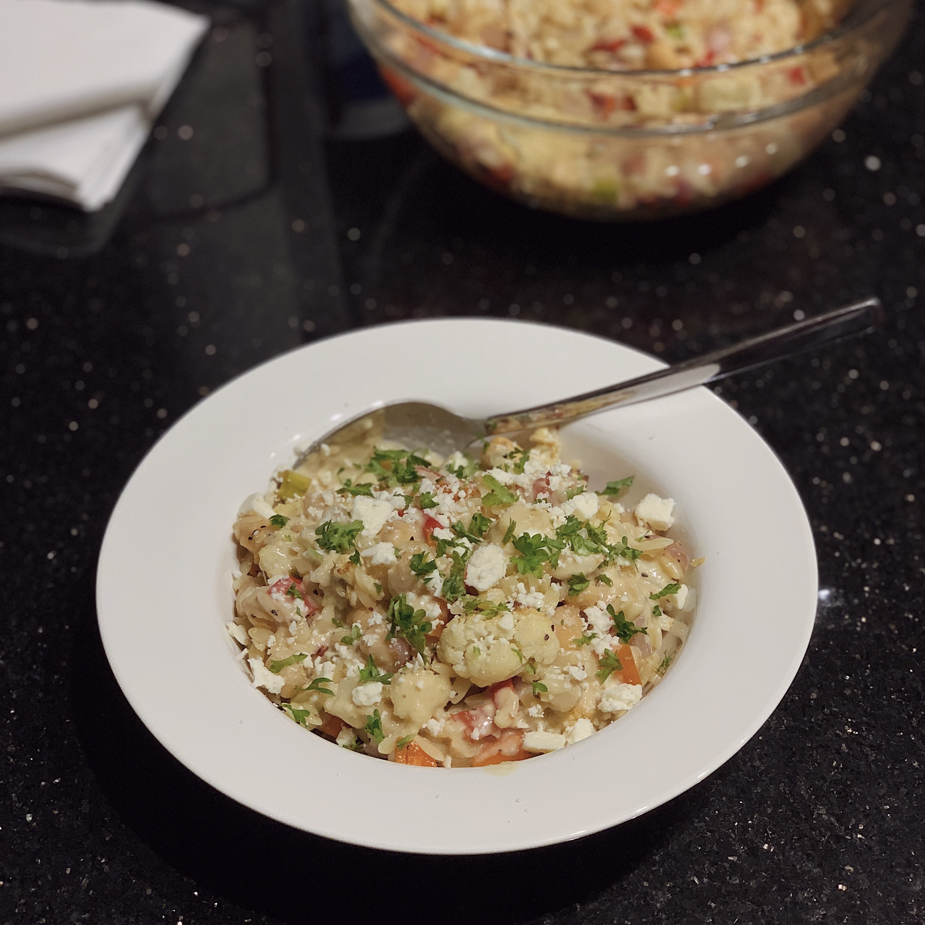 A bowl of Vegan Warm Orzo Salad with a spoon.